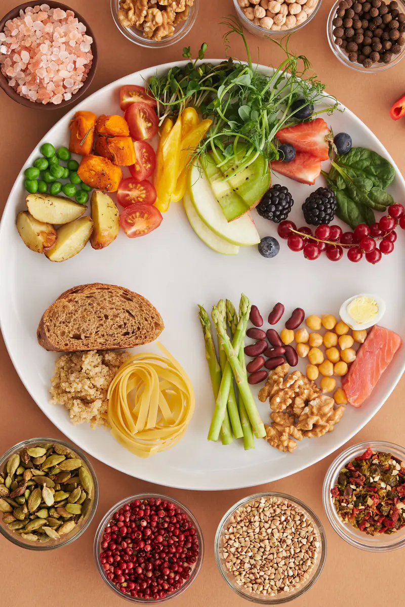A plate of vegetables, fruit, grains and fish, photographed from above.